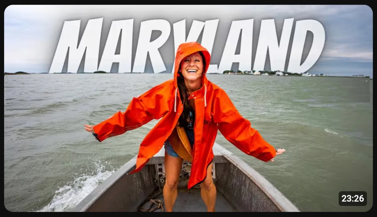 Travel YouTube thumbnail from Kara and Nate featuring a creator in a bright orange rain jacket on a boat with large white text that reads Maryland